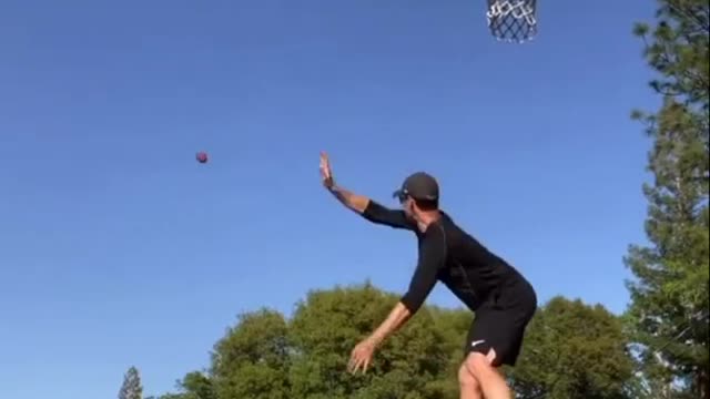 Guy Throws Ball Into Basketball Hoop While Balancing On Slackline