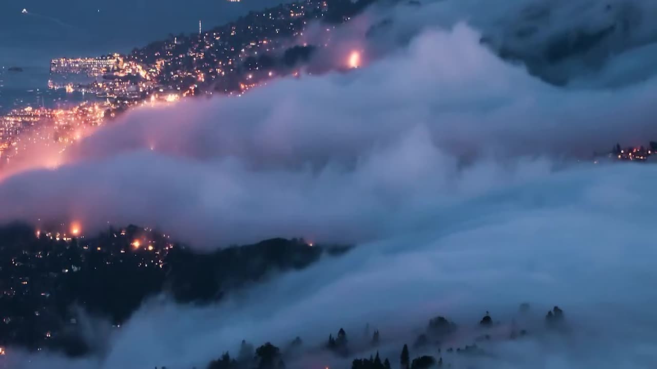 Fog waterfalls pouring into San Francisco after sunset