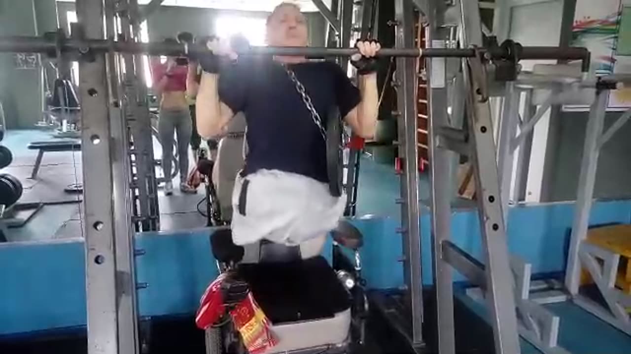 A guy without legs pulls up on a horizontal bar with a pancake of 10 kg.