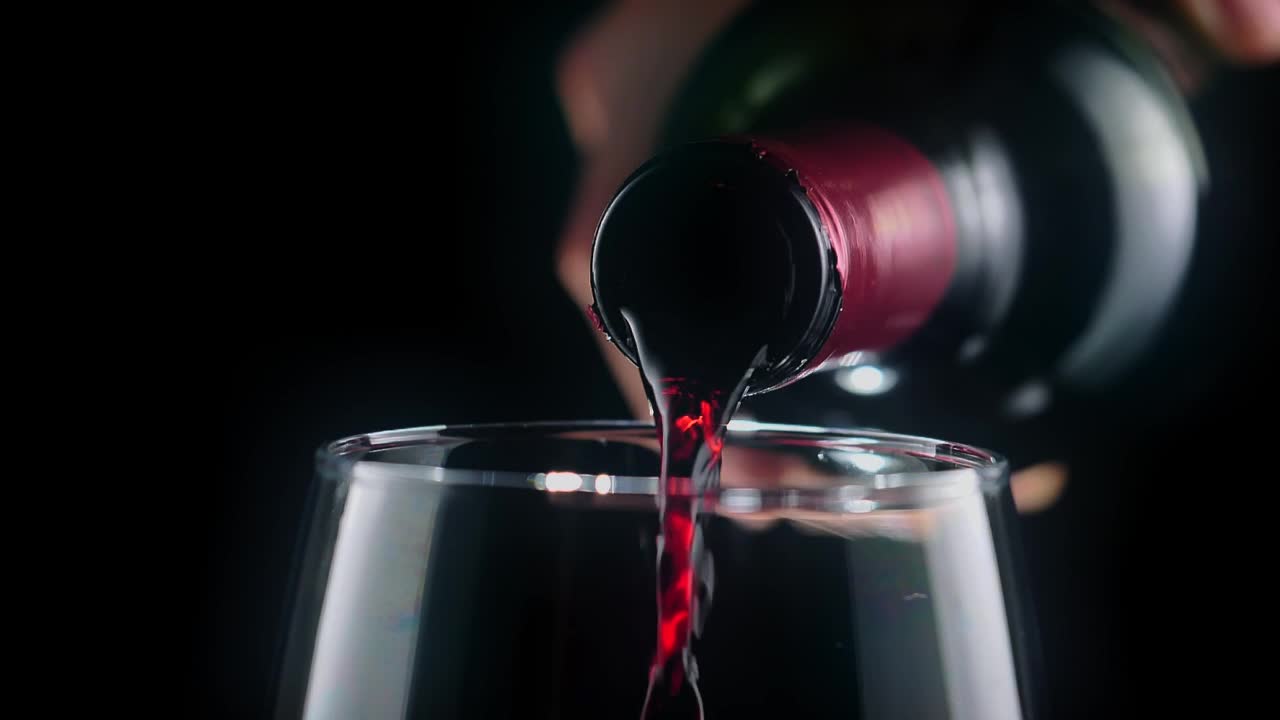 Pouring red wine from a bottle, very close view