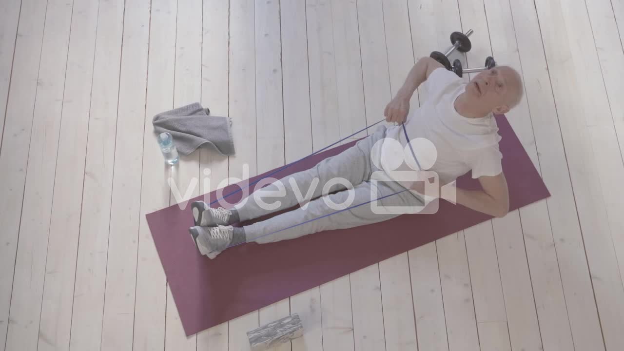 Old Man Using A Stretching Band And Exercising On Yoga Mat At Home 1