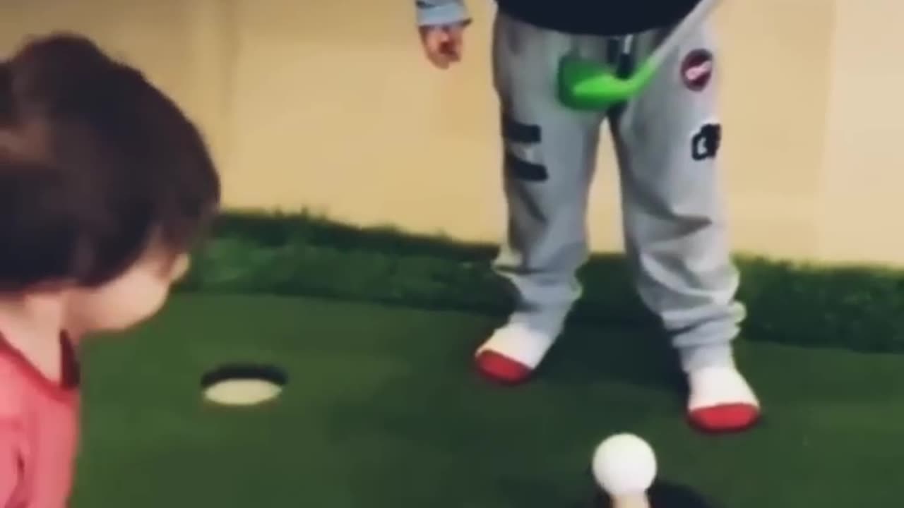 Child tries to hit golf ball