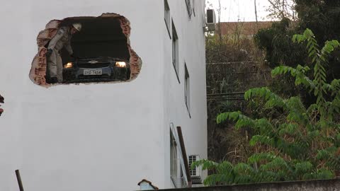 Car Drives Through Building Wall