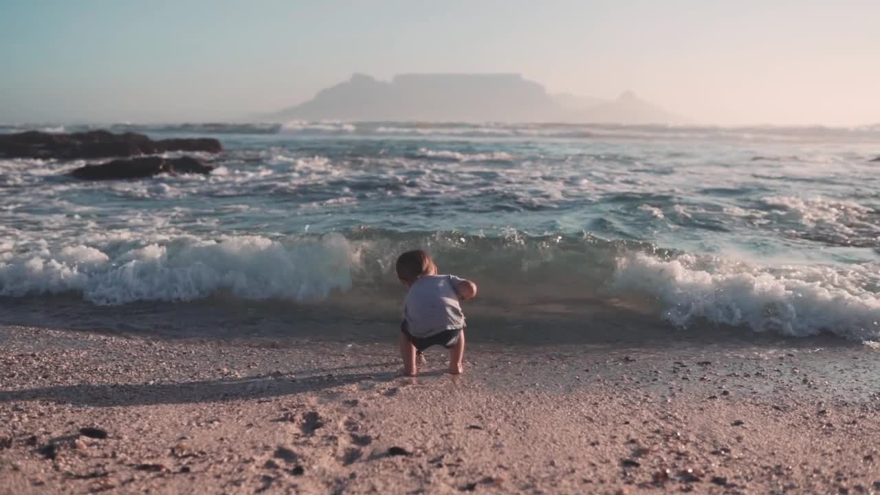 Mother Helping Her Child Get Up From A Stumble Cause By The Sea Waves