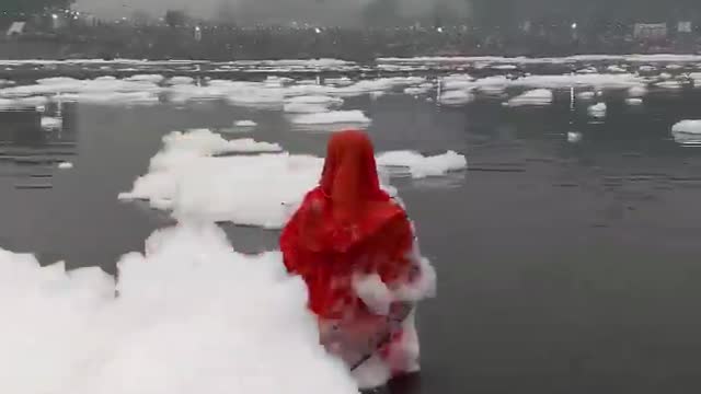 Mulher orando no rio Yamuna enquanto a espuma