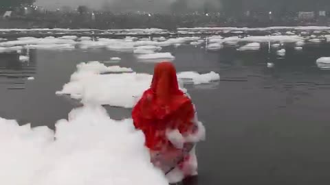 Mulher orando no rio Yamuna enquanto a espuma