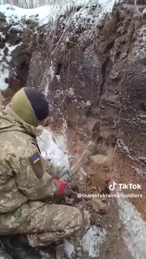 Ukrainian soldier resorts to using an axe to "dig" a trench because the ground is frozen