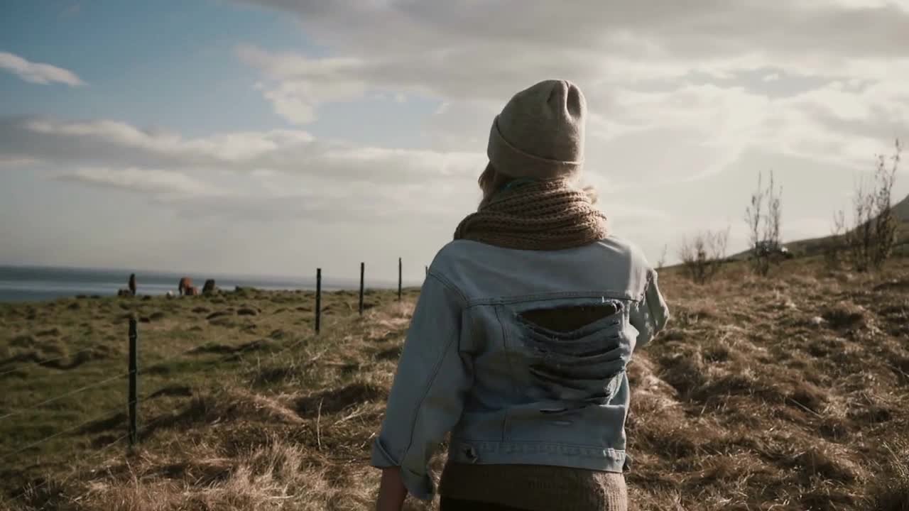 Back view of young stylish woman walking on the nature