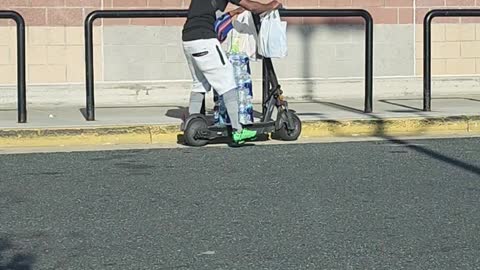 Man Precariously Stacks Bottles of Water on Scooter