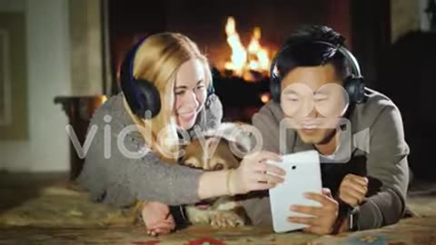 Young Couple Enjoys Tablet Lie Near Fireplace