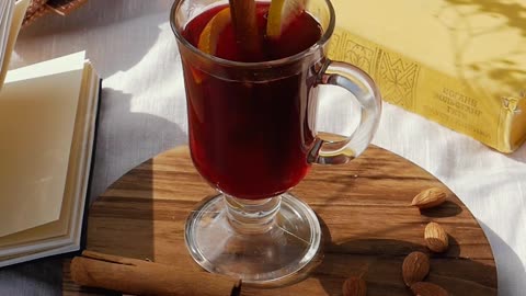 A cup of tea dipped in it is a cinnamon stick and a lemon next to it