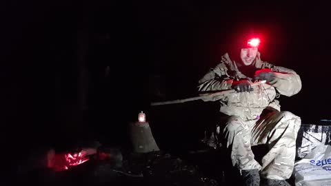 Some camp chores around the campfire. Fashioning a stick to make a small stake .