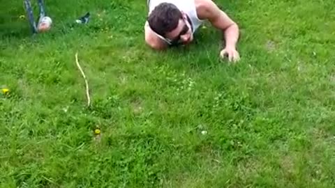 Man in white sleevless shirt and glasses tries to jump over picnic table but racks himself