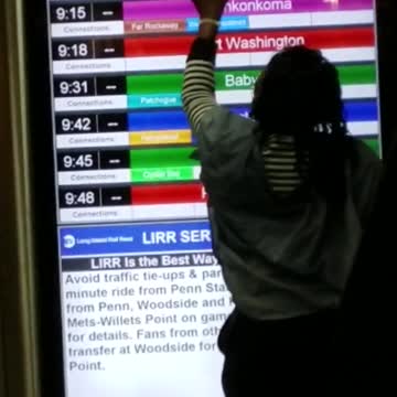 Woman rubs white phone along a screen in subway staion