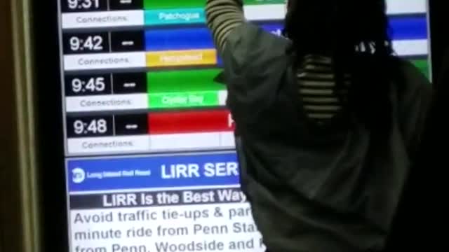 Woman rubs white phone along a screen in subway staion