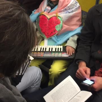 Guy dresses as fox on subway playing piano with strawberry necklace