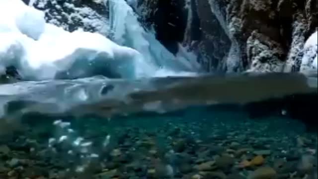 Beautiful nature Snow falling on crystal clear Alaska glacial melt water captured.