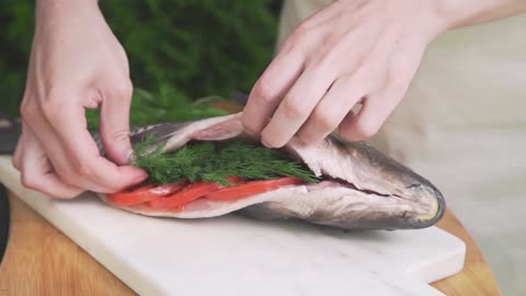 housewife is stuffing raw fish with fennel carp fish on the board cooking fish