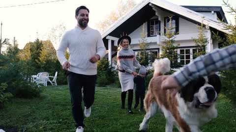 Happy family run and play with their big dog near the house in nature