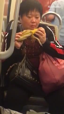 Woman eating corn on the cob on subway
