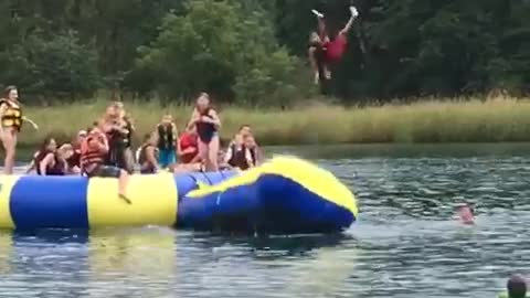 Dad man launches kid off of inflatable bean into water lake