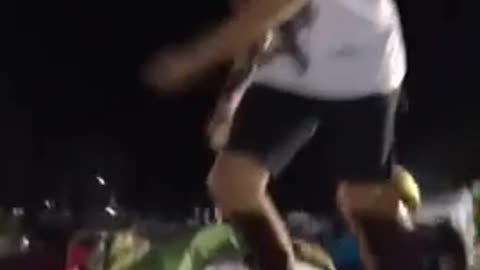 White headband guy jumps off table into cardboard box in front of tents