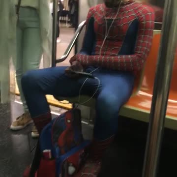 Man in spiderman suit and back pack blue hate subway