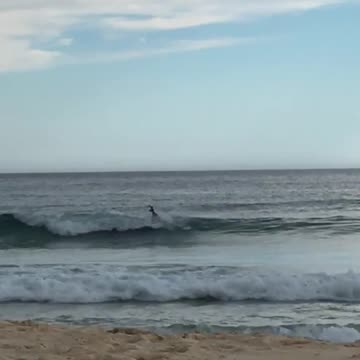 Guy on surfboard at beach falls down in wave