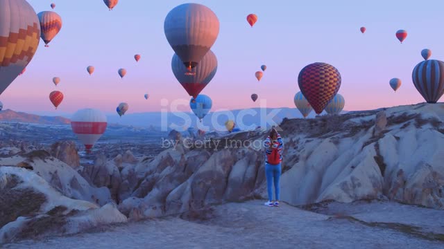 Female traveler with backpack looking to the air baloons. sporty girl and a lot of hot air balloons