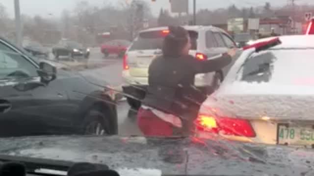 Driver stopped in traffic jumps out to clean stranger's windshield