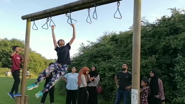 Kid doing the monkey bars better than her brother.