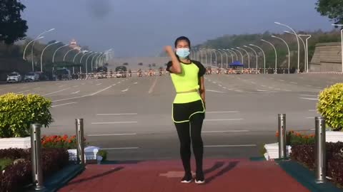 A Military convoy reaching the parliament can be seen behind the woman as she performs aerobics.