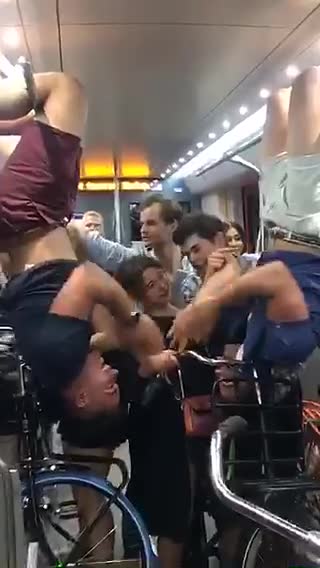 Two bikers play patty cake upside down on subway