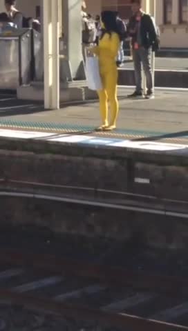 A woman in yellow body suit standing on subway platform