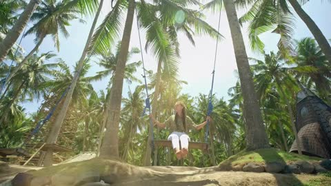 Woman swinging in the jungle on the beach