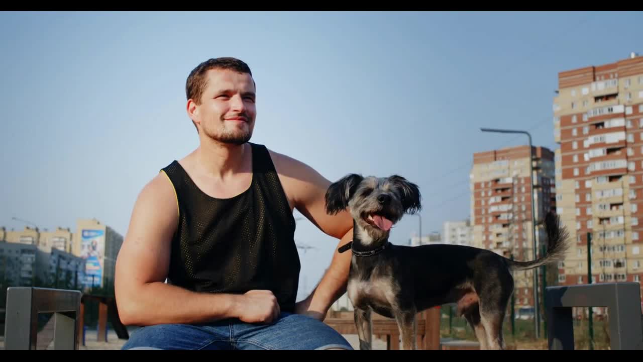 Carefree man with schnauzer dog sitting on city bench looking away Cheerful owner together happy dog