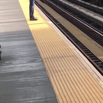 Man black hat standing on yellow line incoming train