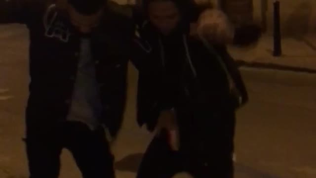 Two guys dance in the middle of the street at night
