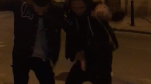 Two guys dance in the middle of the street at night