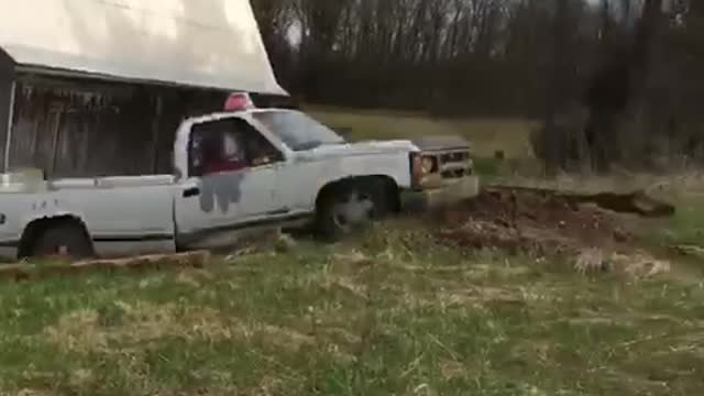 White pick up truck goes up dirt ramp
