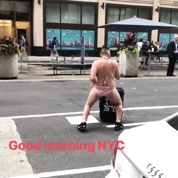Big guy in bikini dancing in streets with i heart ny luggage