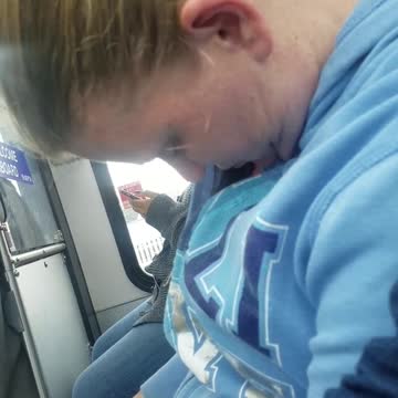 Woman with blue sweater asleep on train