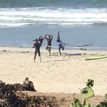 Girl sees three surfers on the beach posing for a picture