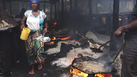 Black African People Working in Smoke - Frying Fish on the Market in Bagamoyo