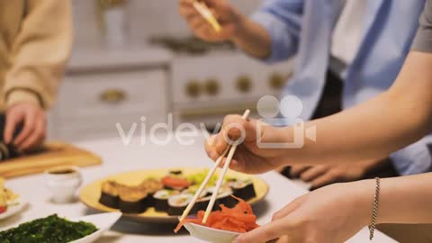 Close View Of A Plate Of Sushi And Hands Holding Japanese Chopsticks