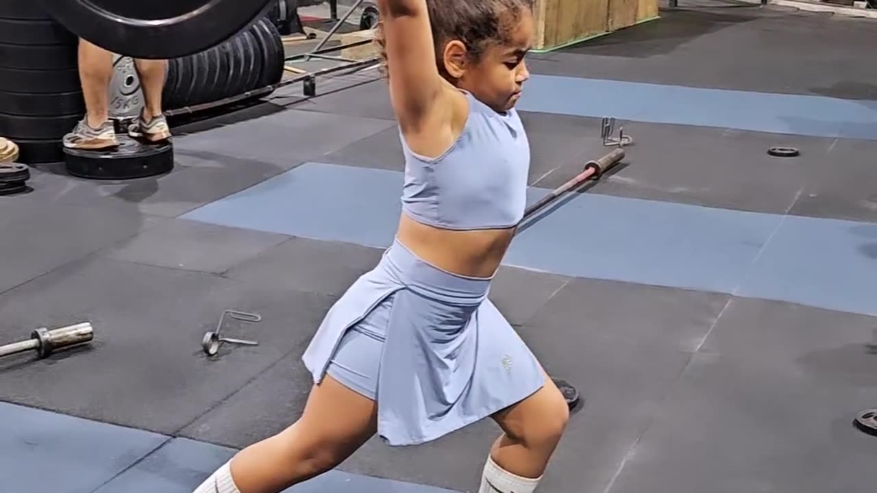 Small girl weight lifting in gym