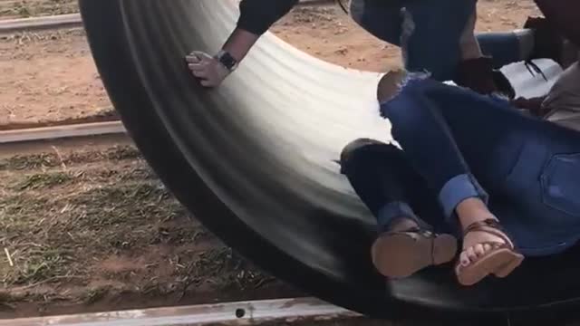 Two girls rolling in a black tube girl in red falls over