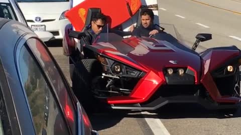 Guy in red car backing up with two surfboards in back