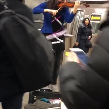 Girl plays the violin and hula hoops in subway station