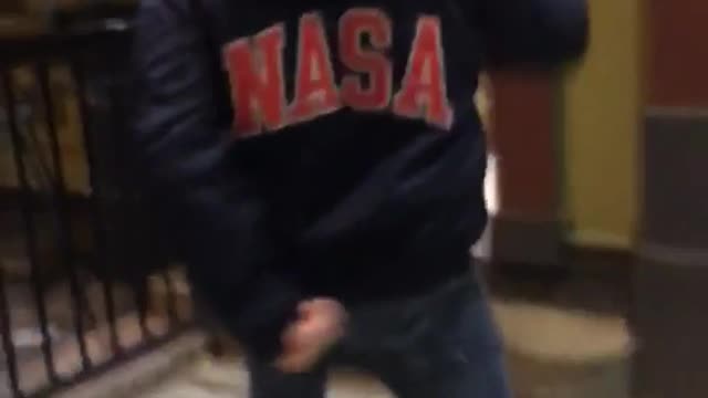 Guy in blue nasa jacket walking to door waving arms